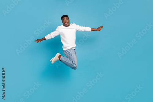 Full length portrait of overjoyed energetic person flight raise arms isolated on blue color background