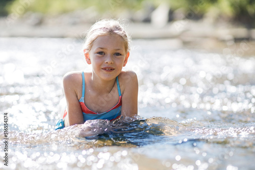 A child girl bathing in the river, summer vacation near the water.