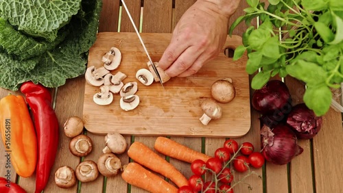 Close-up with chef's hands cutting mushrooms on a wooden board.