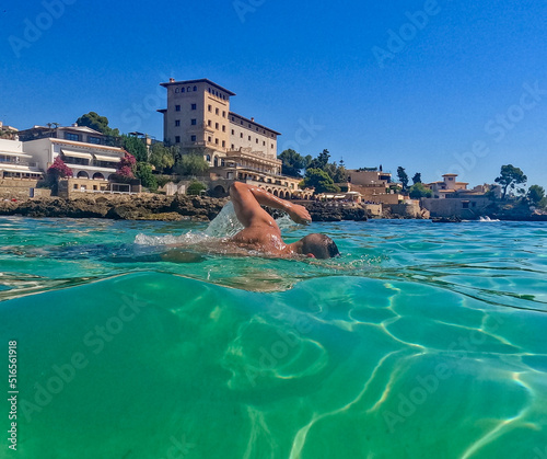 Beautiful scene of a man swimming crawl sltyle in a blue crystal clear watter beach. Concept of sport, holiday and travel. 