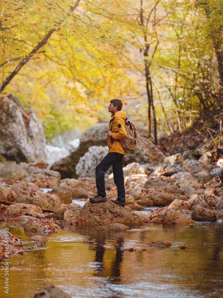 Travel and road trip concept at autumn. Adventure and active lifestyle in nature. Tourist hiking in forest. Caucasian man in yellow jacket walks in woods. Travel and road trip concept at autumn. Adventure and active lifestyle in nature. Tourist hiking in forest. Caucasian man in yellow jacket walks in woods.