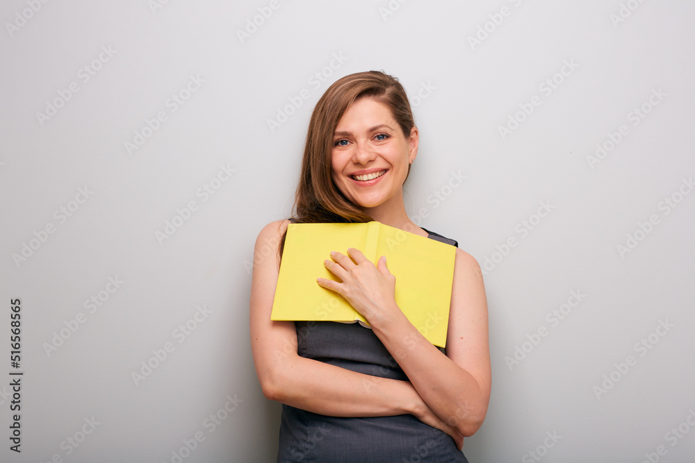 Smiling business woman in gray dress holding yellow book. isolated female business person portrait. Smiling business woman in gray dress holding yellow book. isolated female business person portrait.