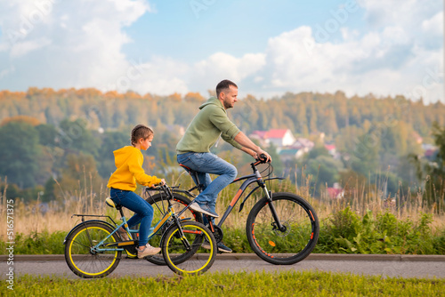 Happy father and daughter take bike ride in nature in autumn.