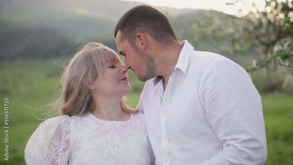 A young pregnant girl and her boyfriend are relaxing in nature. Happy young couple in white shirt and dress. A pregnant woman and her husband are waiting for the birth of a child. Young family.