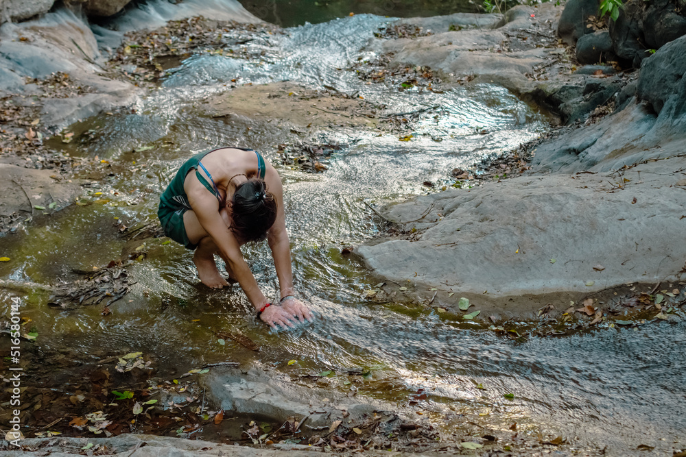 Young Colombian woman making meditation in a river (praying Pachamama) with her hands in the fresh water. Villeta, Cundinamarca, Colombia. Young Colombian woman making meditation in a river (praying Pachamama) with her hands in the fresh water. Villeta, Cundinamarca, Colombia.