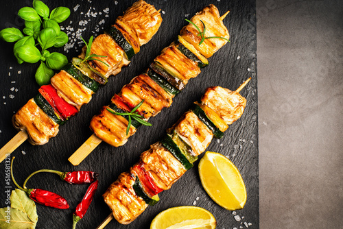 .Chicken shish kebab with zucchini. Top view.Grilled chicken kebab with vegetables on a black background.Grilled pieces of chicken meat on skewers.
