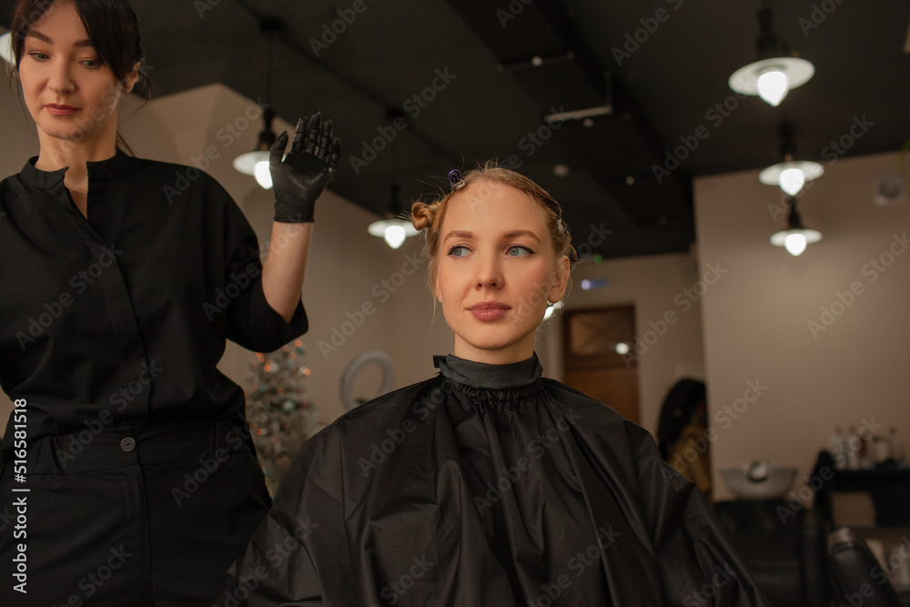 Obraz premium Close-up of female hands holding the hair rows in professional hairstyles salon. The hairdresser paints or makes keratin to a girl in a professional salon