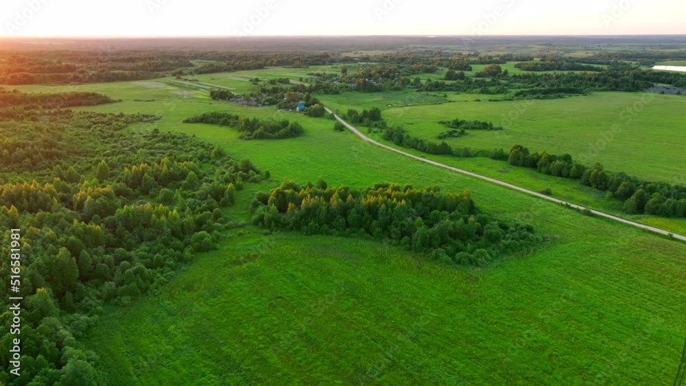 Field with a forest, a road in the village. Village wooden house. Country houses in countryside, aerial view. Rural building and farmhouse in countryside. Rural area on sunset, drone view. Field with a forest, a road in the village. Village wooden house. Country houses in countryside, aerial view. Rural building and farmhouse in countryside. Rural area on sunset, drone view.