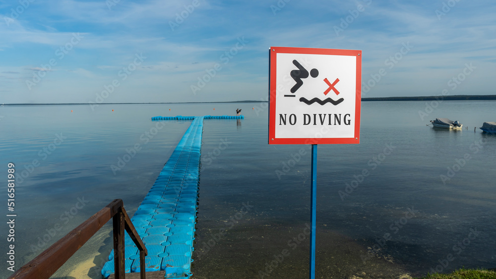 No Diving sign at beach, lake Naroch, Belarus. Warning sign of shallow water. Warning notice sign do not jump in water.