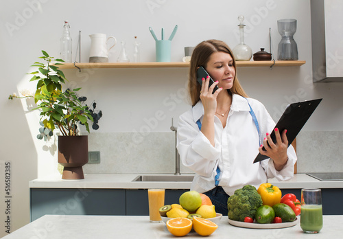 The nutritionist advises the patient online by phone. Nutraceutical is in the kitchen with fresh fruits and vegetables. photo