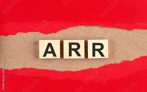 ARR word on wooden cubes on red torn paper , financial concept background