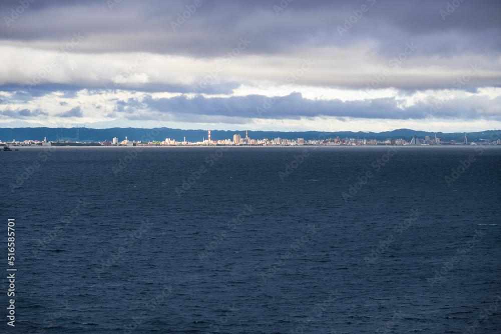 Obraz premium 浅虫温泉から海のかなたに眺める 雨上がりの朝日を浴びる青森市街