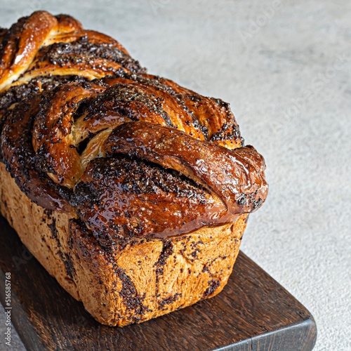 Freshly baked brioche/Babka with poppy seeds and chocolate on a wooden board. Braided dessert bread. Homemade baking, national pastries. Estonian kringle in the shape of a brick. photo