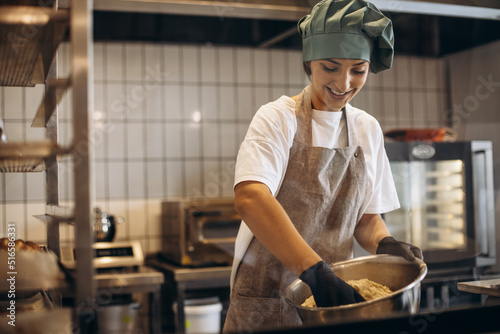 Slika na platnu Female pastry baker at the kitchen making dough for croissants