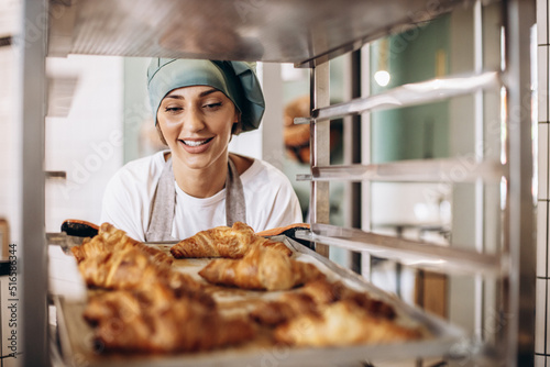 Foto Female baker at the kitchen holding croissant