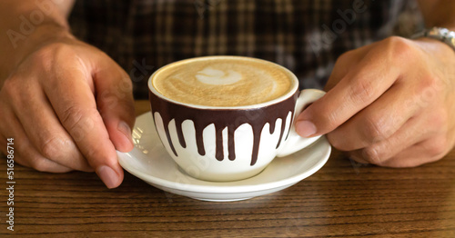 Man holding cappuccino coffee cup at restaurant