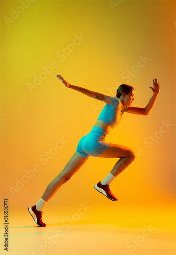 Professional longjumper. One female athlete in sports uniform jumping isolated on yellow background. Concept of sport  action  motion  speed.