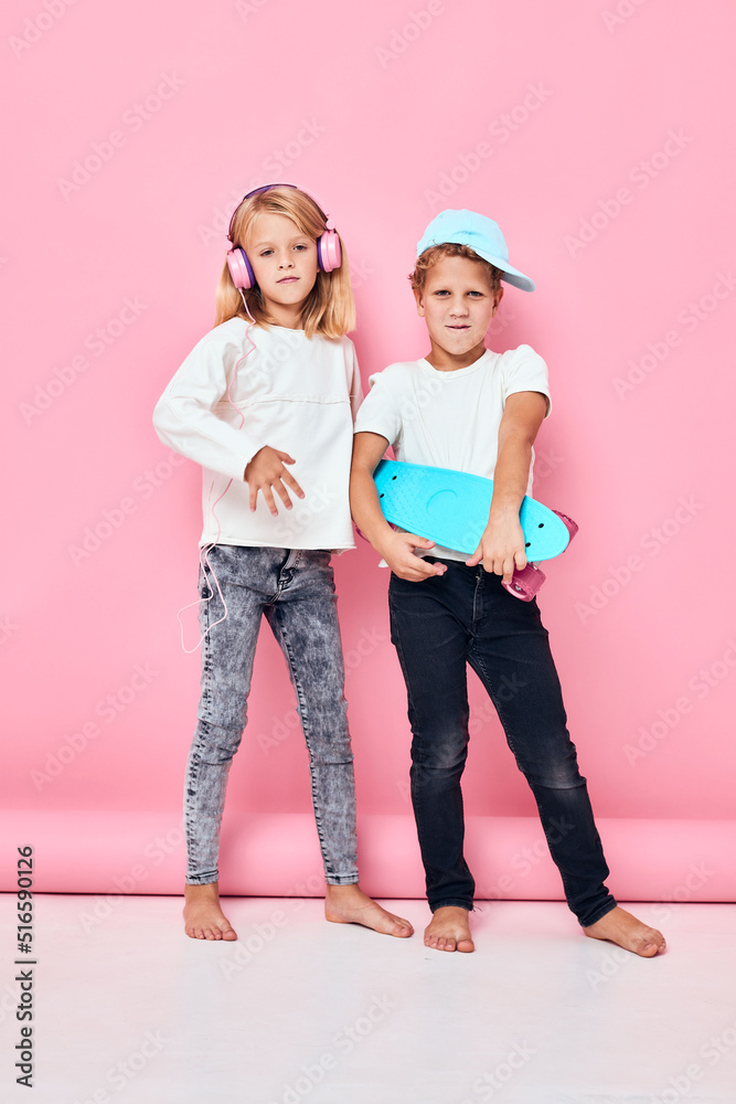 Fototapeta premium a boy in a cap and a girl skateboard headphones playing isolated background