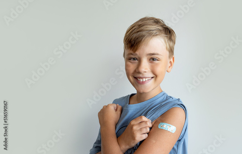 Child after vaccination with a adhesive band-aid patch arm bandage to prevent any infection over white background. Positive concept of healthy lifestyle and care.