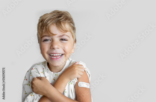 Child after vaccination with a adhesive band-aid patch arm bandage to prevent any infection over white background. Positive concept of healthy lifestyle and care.