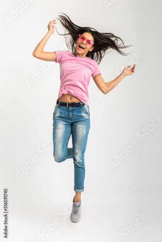 attractive woman in pink t-shirt and sunglasses jumping