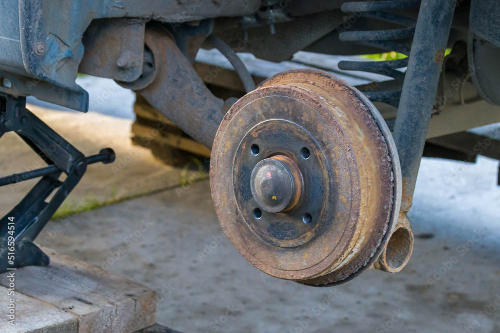 close-up of a rusty brake disc, a car without a wheel close-up of a rusty brake disc, a car without a wheel