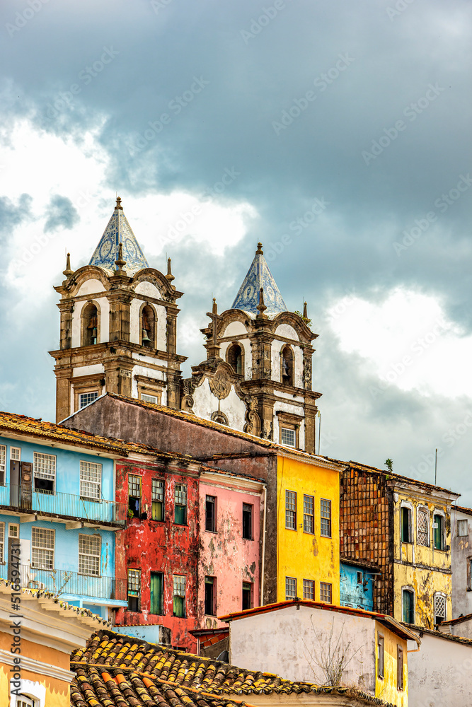 Historic baroque church tower behind the facades of old colonial style houses in Pelourinho in the city of Salvador, Bahia