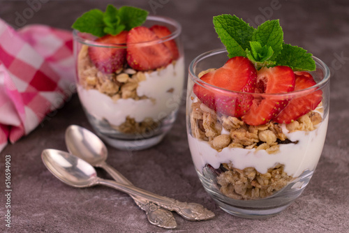 Two strawberry desserts with yogurt and granola.	