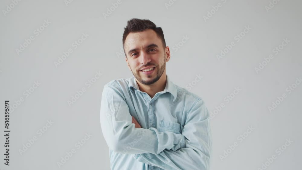 Young Caucasian Brunet Man is Looking at the Camera on a Light Gray Background. Studio Male Face Portrait. Natural Day Light. Young Caucasian Brunet Man is Looking at the Camera on a Light Gray Background. Studio Male Face Portrait. Natural Day Light.