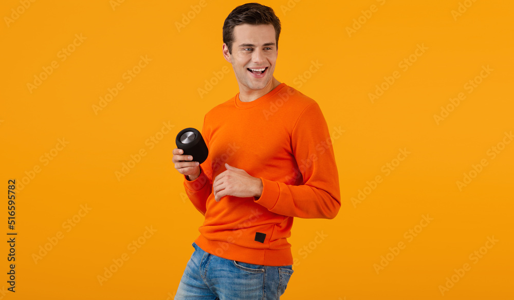 stylish young man holding wireless speaker - obrazy, fototapety, plakaty 