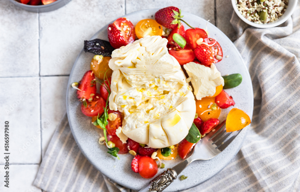 Salad with burrata cheese, cherry tomatoes and strawberry with microgreen and olive oil. Traditional Italian burrata cheese. Summer food. Healthy eating concept. Keto diet. Salad with burrata cheese, cherry tomatoes and strawberry with microgreen and olive oil. Traditional Italian burrata cheese. Summer food. Healthy eating concept. Keto diet.