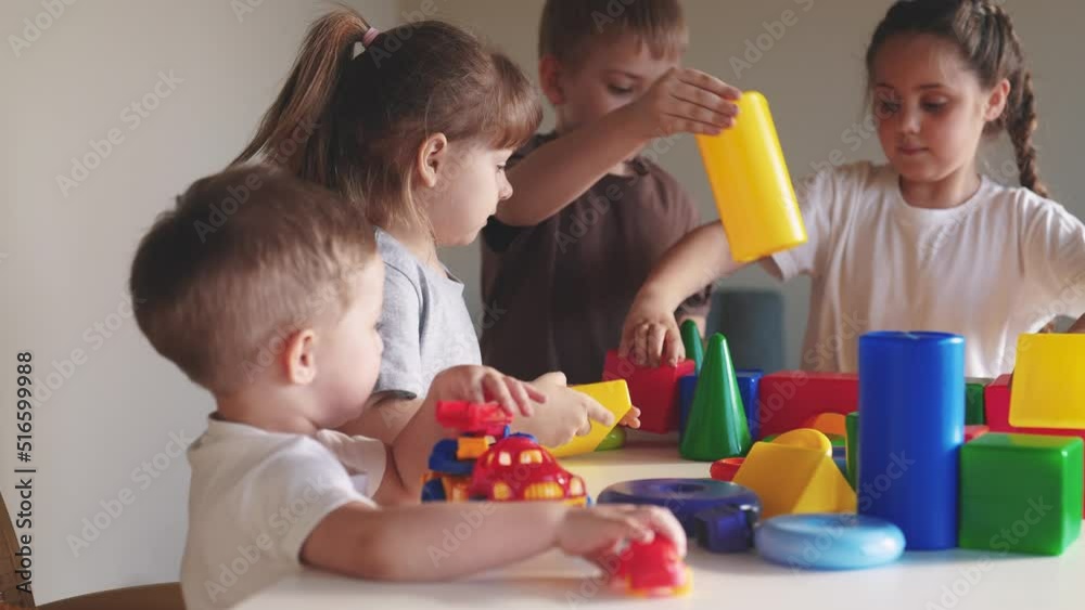 kids girl and baby boy play in kindergarten. a group of children play toys cubes and cars on the table in kindergarten. happy family preschool education indoor concept. nursery baby toddler home kids girl and baby boy play in kindergarten. a group of children play toys cubes and cars on the table in kindergarten. happy family preschool education indoor concept. nursery baby toddler home