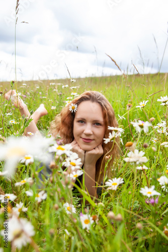 Portrait of cute young girl in dress with wild flowers in summer