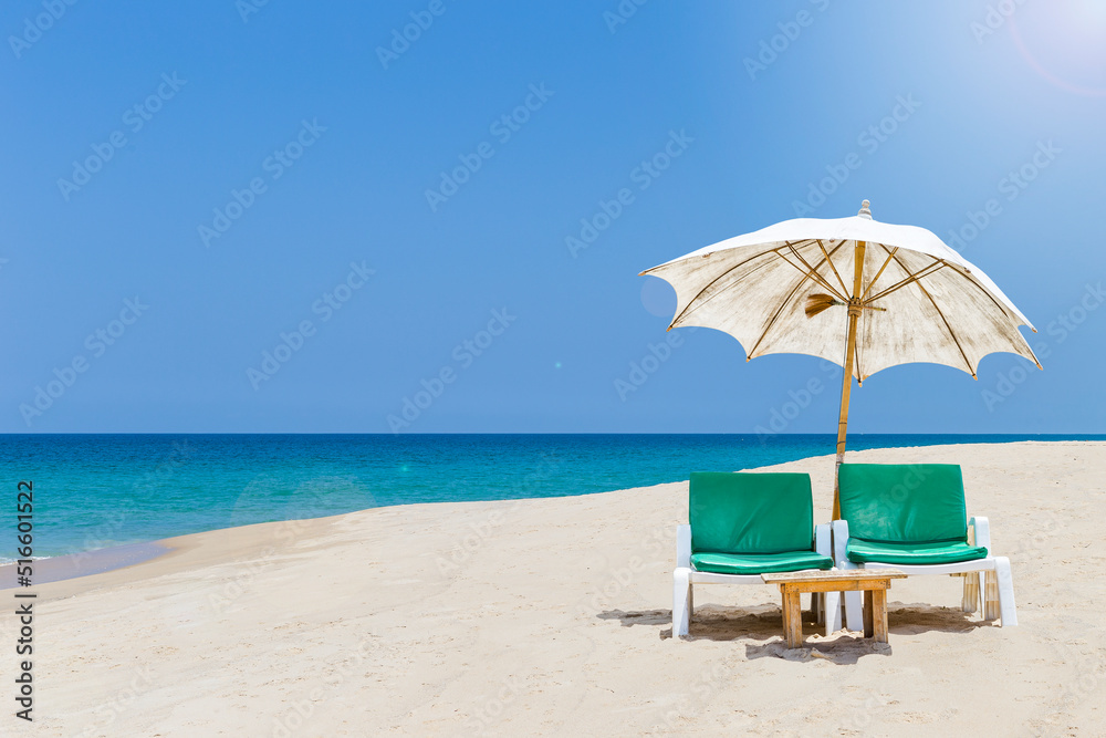 Tropical summer season, relaxing by the beach, beach chair under old umbrella on sandy beach, summer outdoor day light
