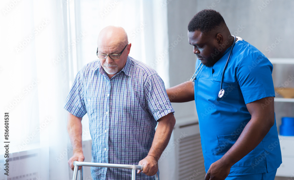 Fototapeta premium Professional doctor helps an elderly man with chronic diseases. Therapist and patient in home interior. Health care and medicine concept.