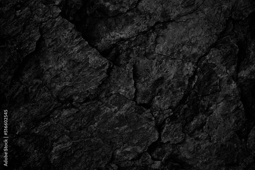 Black rock texture. Rough mountain surface with cracks. Close-up. Stone background with space for design.