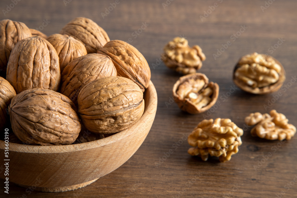 Bowl of walnuts and whole walnut kernels on wooden background,top view Bowl of walnuts and whole walnut kernels on wooden background,top view