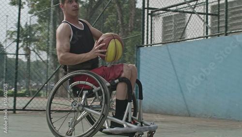 One disabled basketball player playing ball outside. Closeup of paraplegic person on wheelchair action motion. Sport and disability concept © Marco