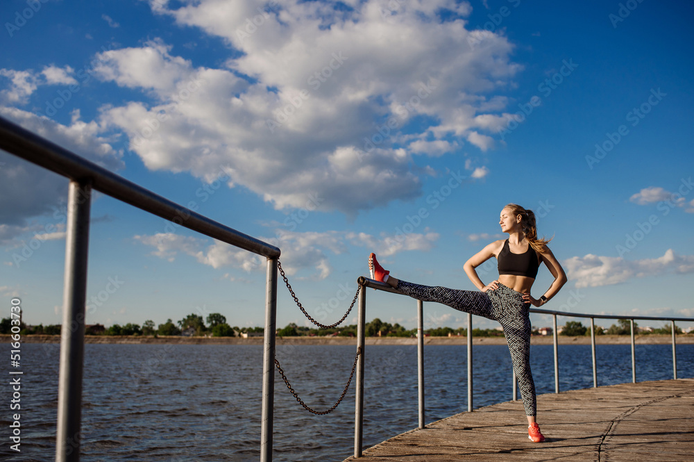 Slim fit woman doing stretching exercises on pier at sunny day Slim fit woman doing stretching exercises on pier at sunny day