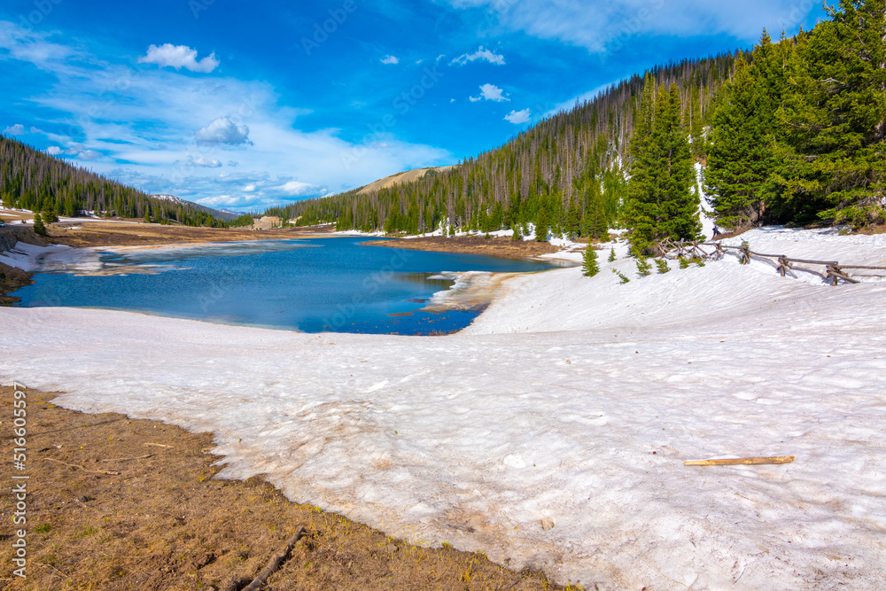 snow by lake in rocky mountains
