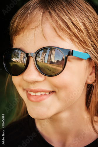 A beautiful girl in sunglasses in which skyscrapers are reflected. Up close
