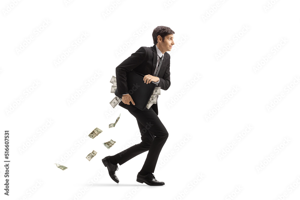 Obraz premium Full length profile shot of a businessman running and holding a briefcase full of money