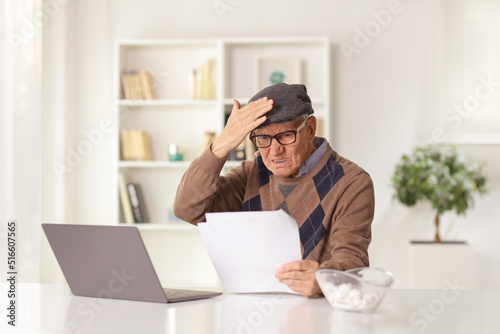 Shocked elderly man reading a document in front of a laptop computer