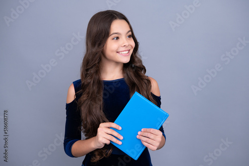 Happy smiling teenager school girl. Schoolchild, teenage student girl hold book on gray isolated studio background. School and education concept. Back to school.