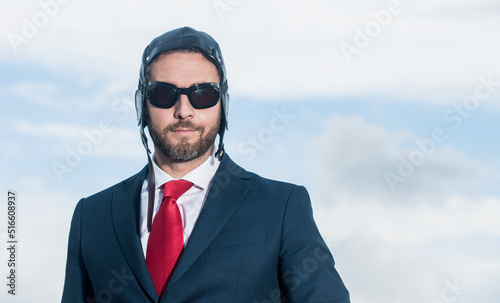 businessman in suit and pilot hat on sky background
