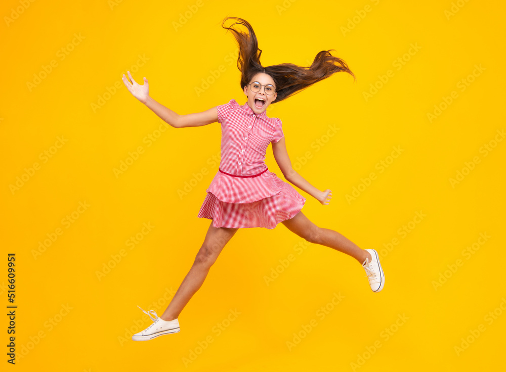 Amazed teen girl. Excited expression, cheerful and glad. Full length cheerful teenager kid jump enjoy rejoice win isolated on yellow background. Small child girl in summer dress jumping. Amazed teen girl. Excited expression, cheerful and glad. Full length cheerful teenager kid jump enjoy rejoice win isolated on yellow background. Small child girl in summer dress jumping.