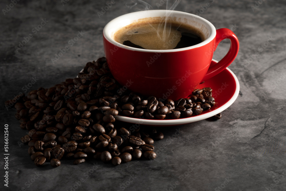 Hot espresso in red coffee mug with coffee beans on concrete