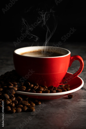 Hot espresso in red coffee mug with coffee beans on concrete