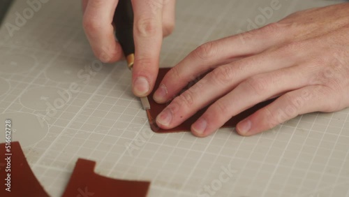 Leather craftsman works in his workshop. Master making leather wallet. Man cuts a leather shape with a bevel cutter. Guy using beveler or edger.