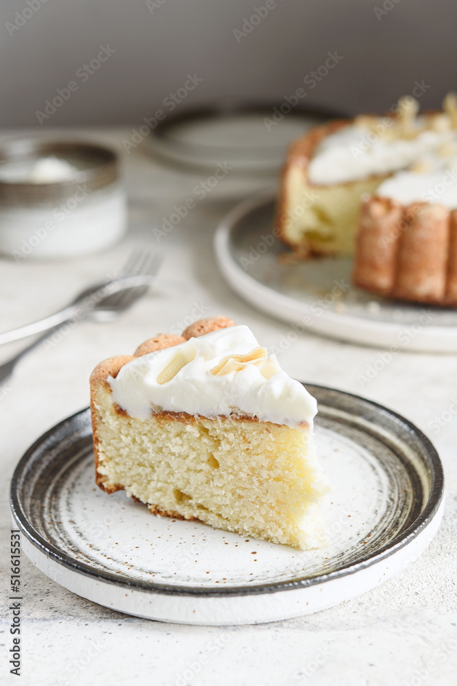 Slice of Homemade Coconut Buttermilk Pound Cake glazed whipped cream and coconut flakes on gray concrete background. Selective focus Slice of Homemade Coconut Buttermilk Pound Cake glazed whipped cream and coconut flakes on gray concrete background. Selective focus